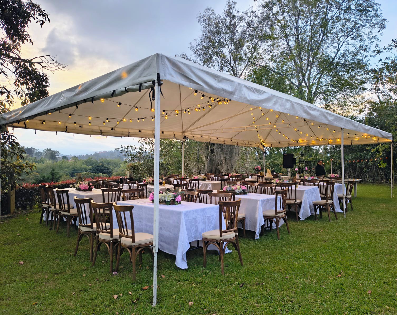 Recepción bajo carpa con mesas montadas y luces